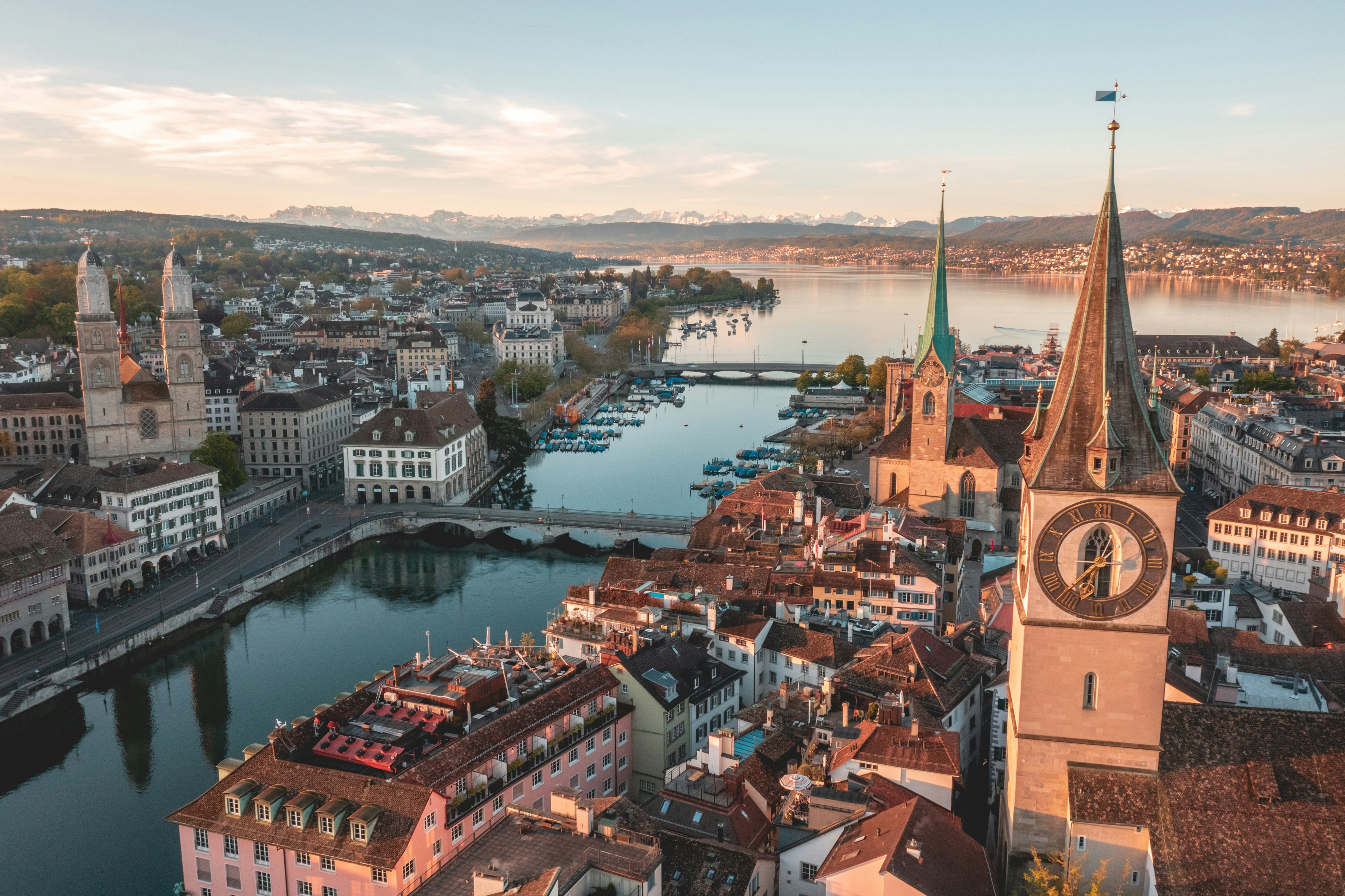 A panoramic view of the town of Interlaken nestled between the turquoise waters of Lake Thun and Lake Brienz, with the Eiger, Mönch, and Jungfrau peaks in the background